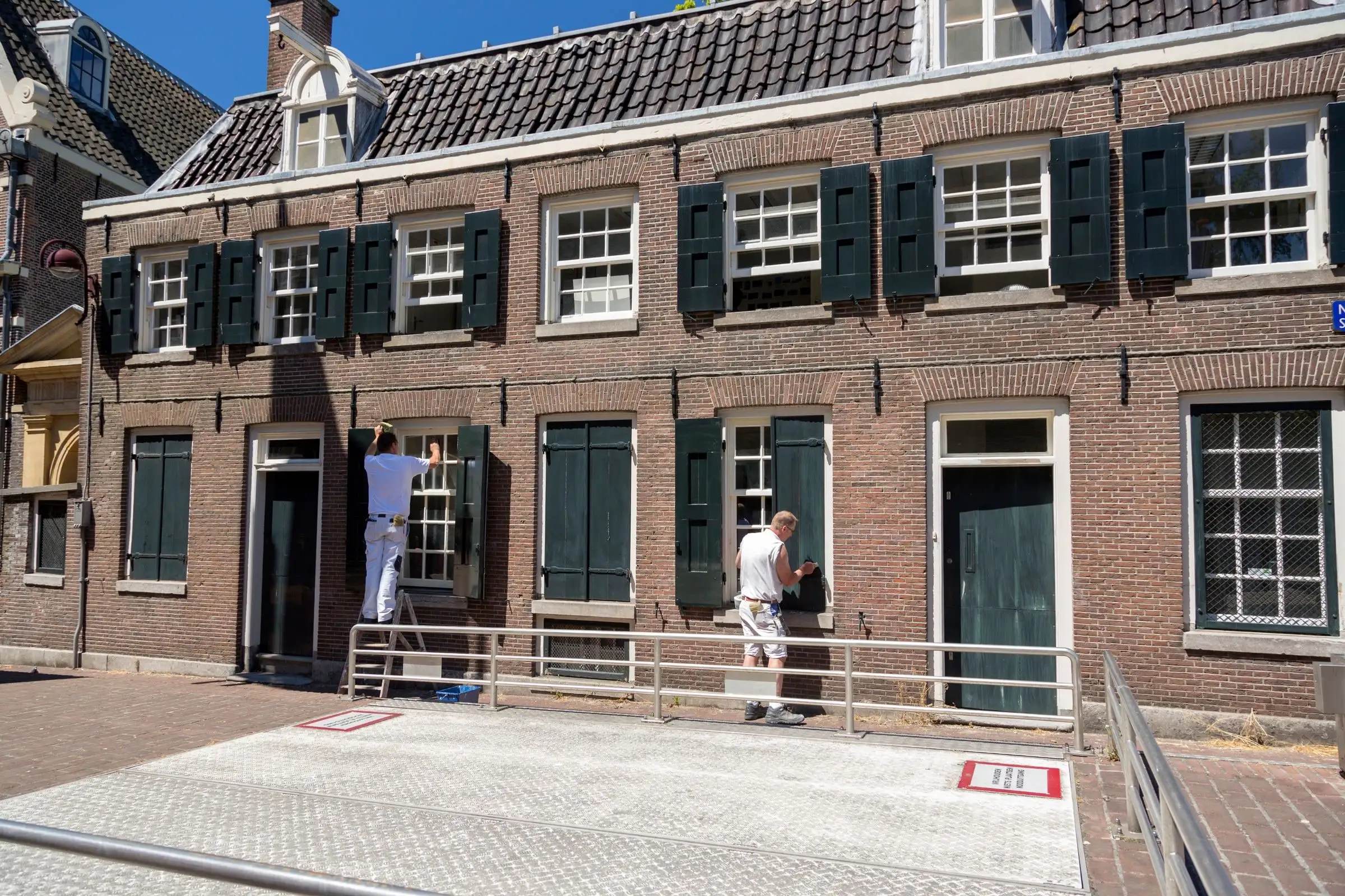 Two painters working on the facade of a brick building