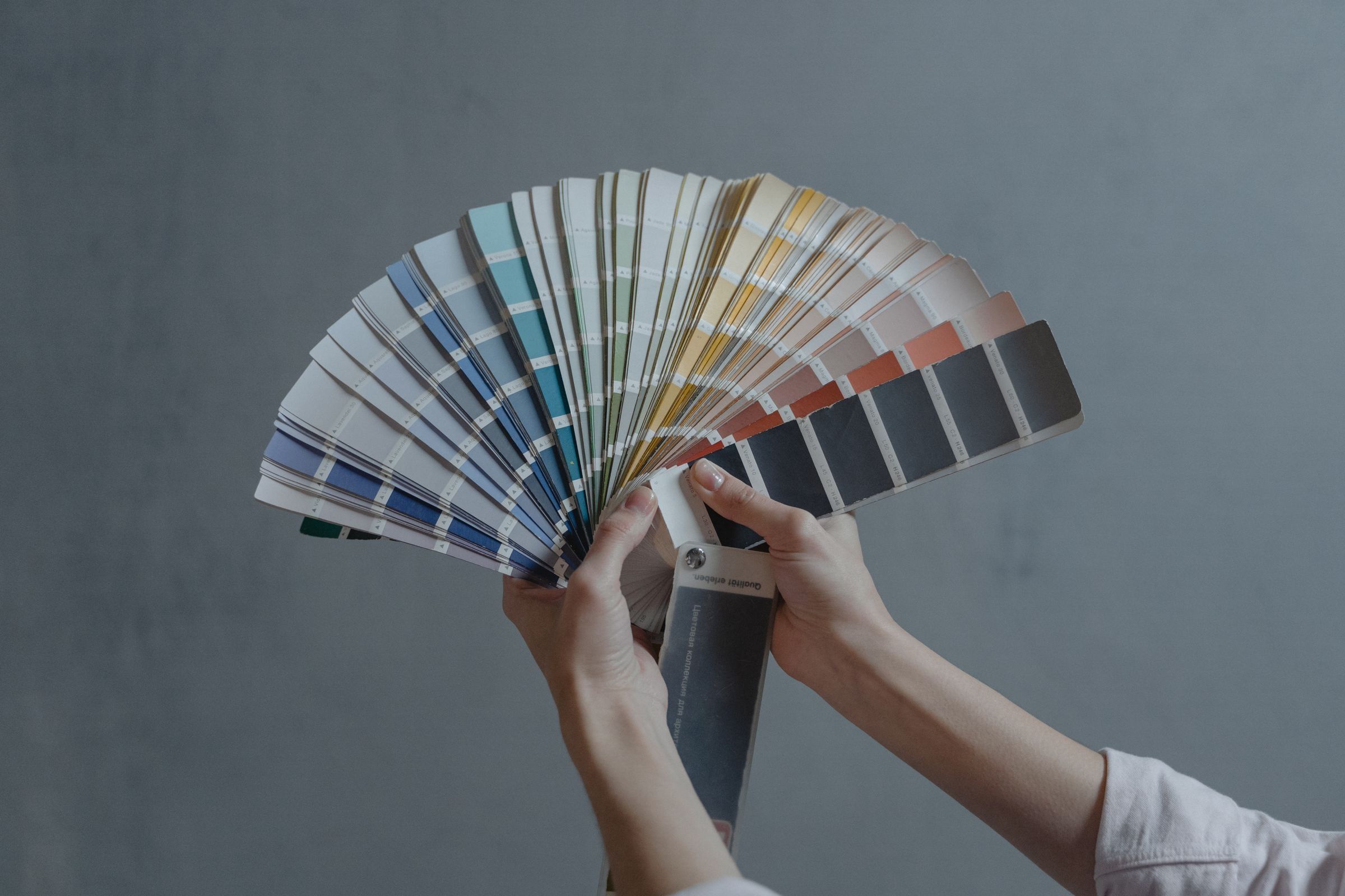 Hands fanning out a deck of paint colour swatches