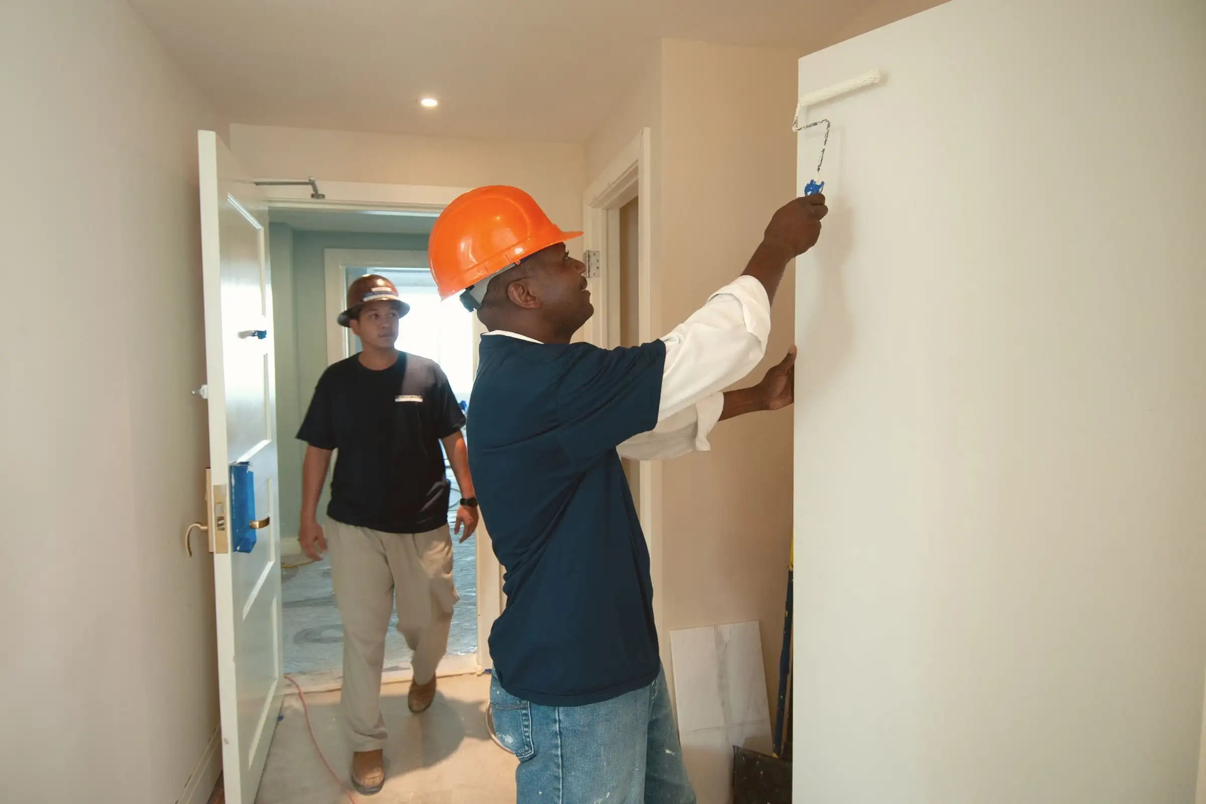 Two painters at work in a bright interior doorway