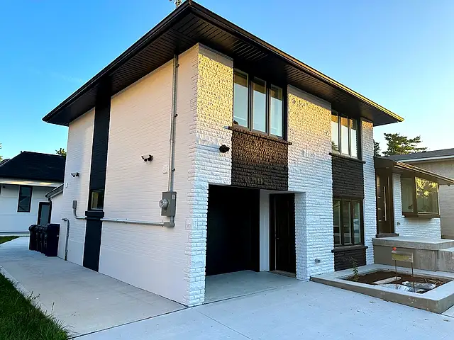 Side and garage corner after painting: white brick with a black accent column