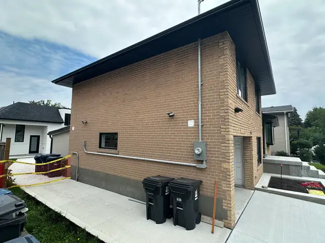Side wall of the tan brick house with the hydro meter, before painting