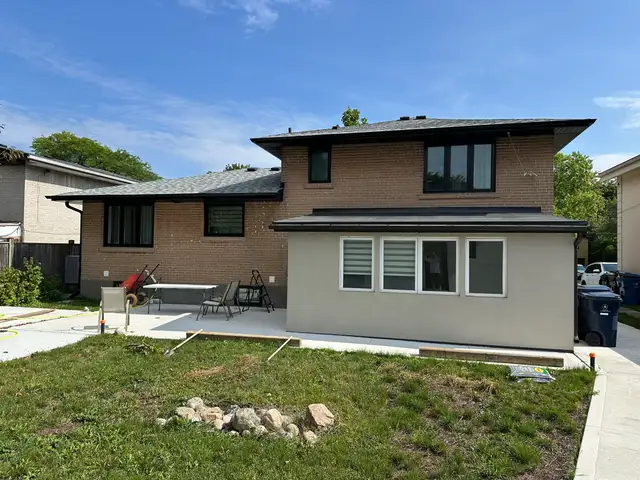 Rear of the house: tan brick upper storey and grey stucco addition, before painting
