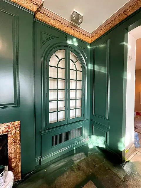 Panelled wall and arched cabinet door finished in deep green