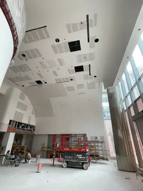 Double-height commercial space with unfinished drywall ceiling and a scissor lift