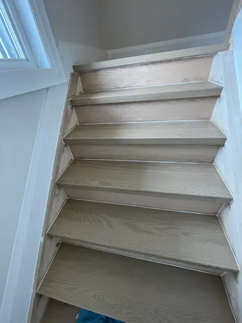 Narrow staircase with pale grey-washed wooden treads and risers