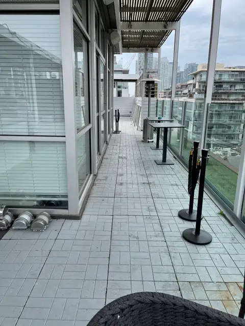 Long condo terrace with plain grey floor tiles and a glass railing