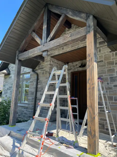 Stone house entrance with grey, weathered timber posts and beams