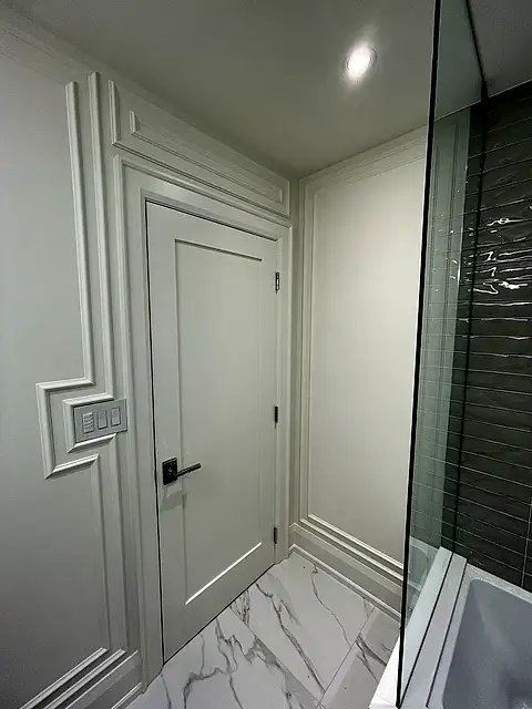 Bathroom entry with white wall mouldings and a white door